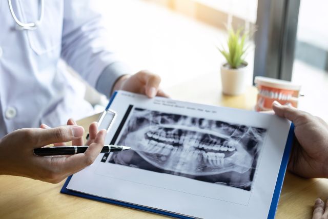 歯のレントゲン写真を見せる歯科医